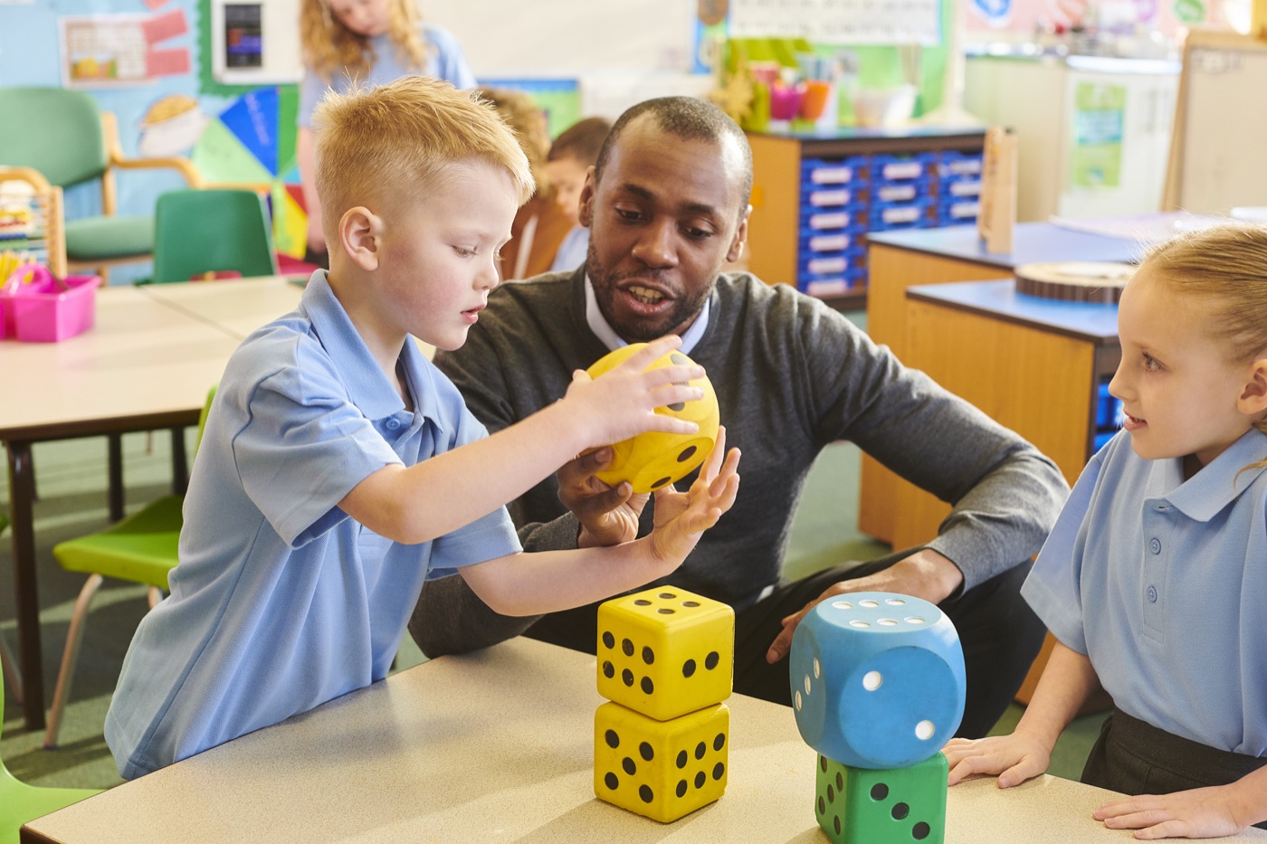 A teacher supporting a young pupil with a hands-on counting activity in class